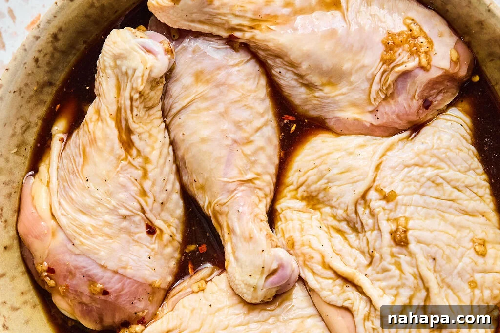 Raw chicken marinating in a bowl with sauce before cooking.