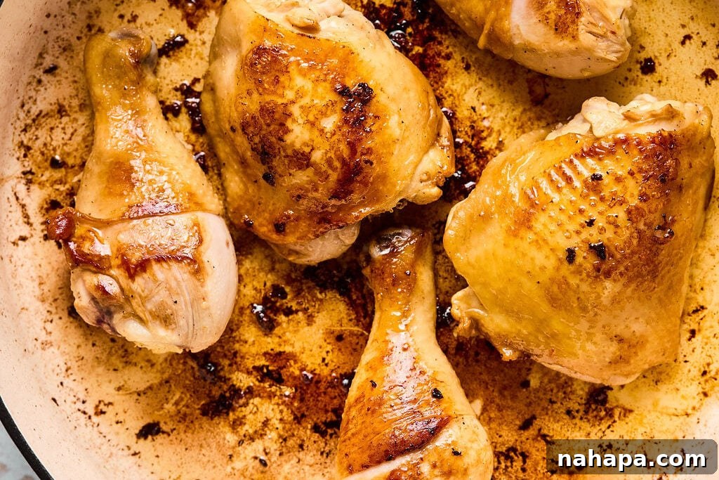 Chicken pieces searing in a large pan, browning nicely.