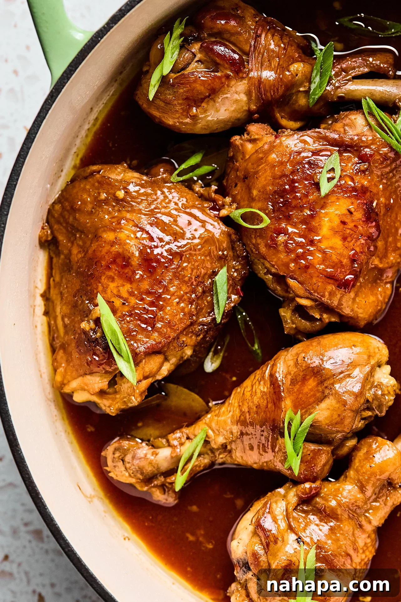 Filipino chicken adobo simmering in a large cast iron pan, ready to serve.