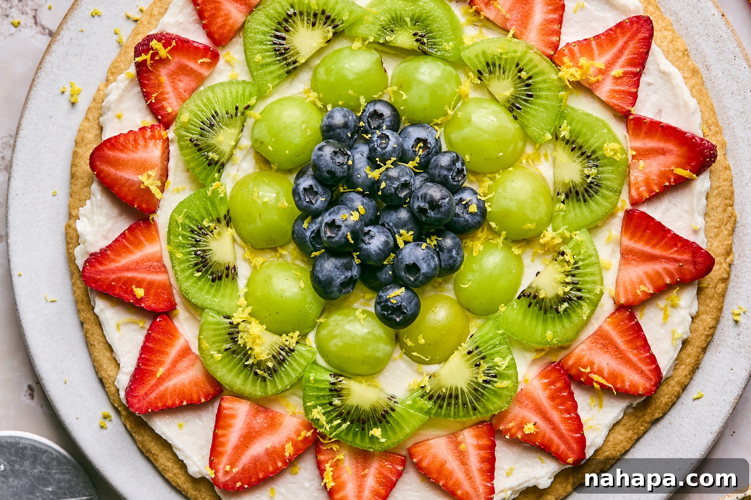 Completed sugar cookie fruit pizza beautifully decorated with a colorful array of fresh fruit.