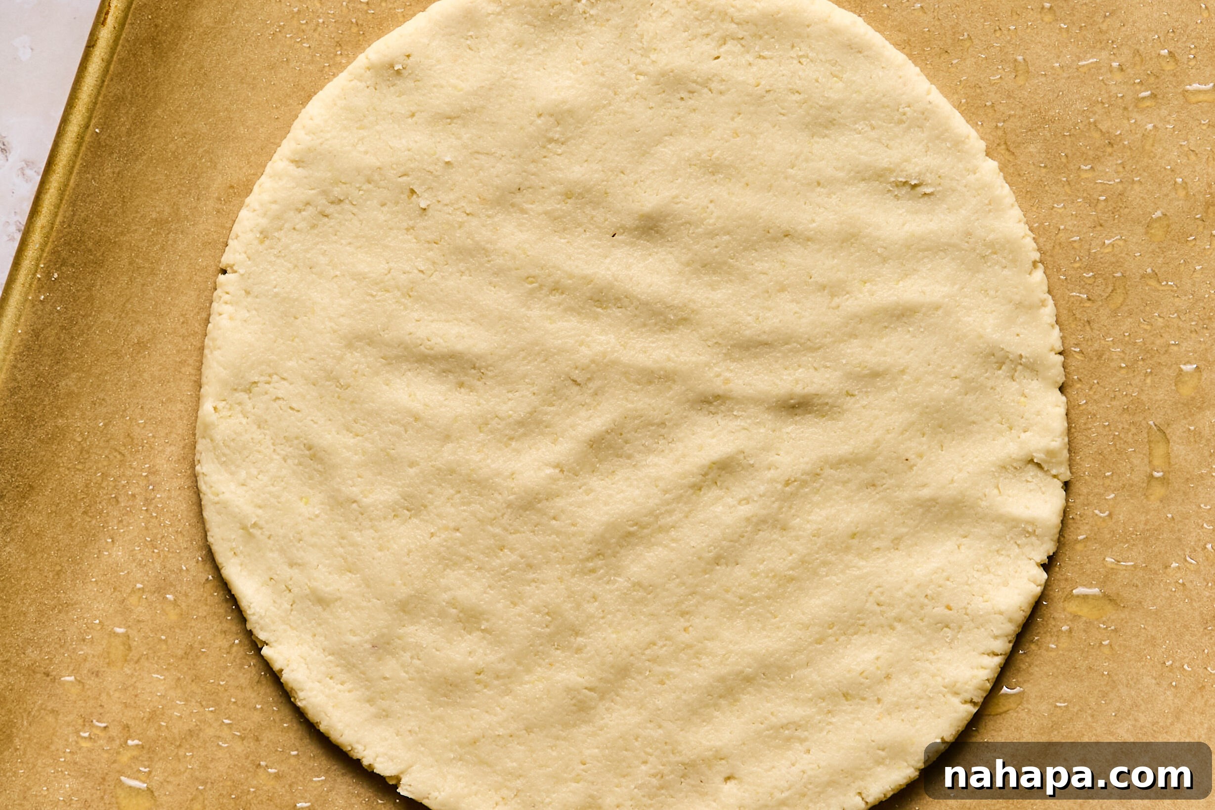 Cookie dough being formed into a perfect circle on a baking sheet.