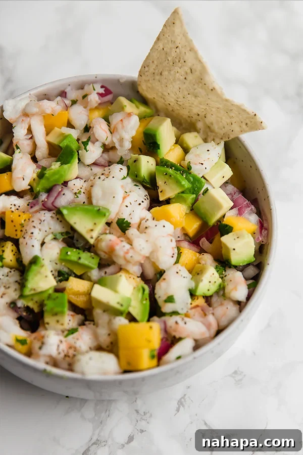 Various ingredients for ceviche: shrimp, lime, mango, red onion, avocado, cilantro on a rustic board.