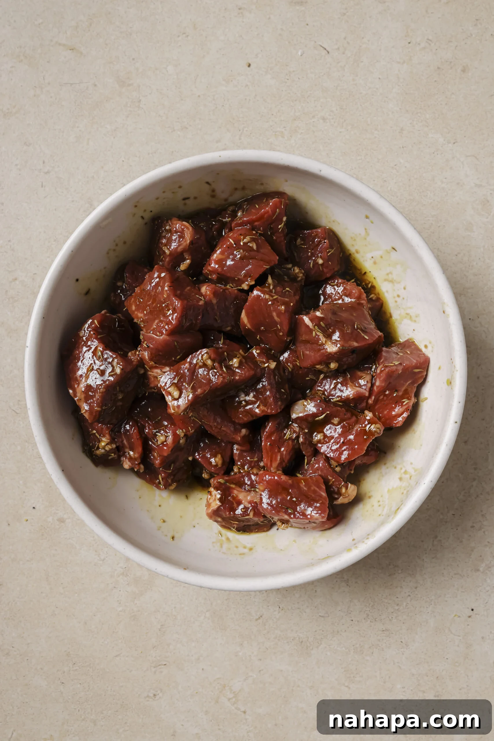 Steak marinating in a balsamic vinegar mixture in a bowl.