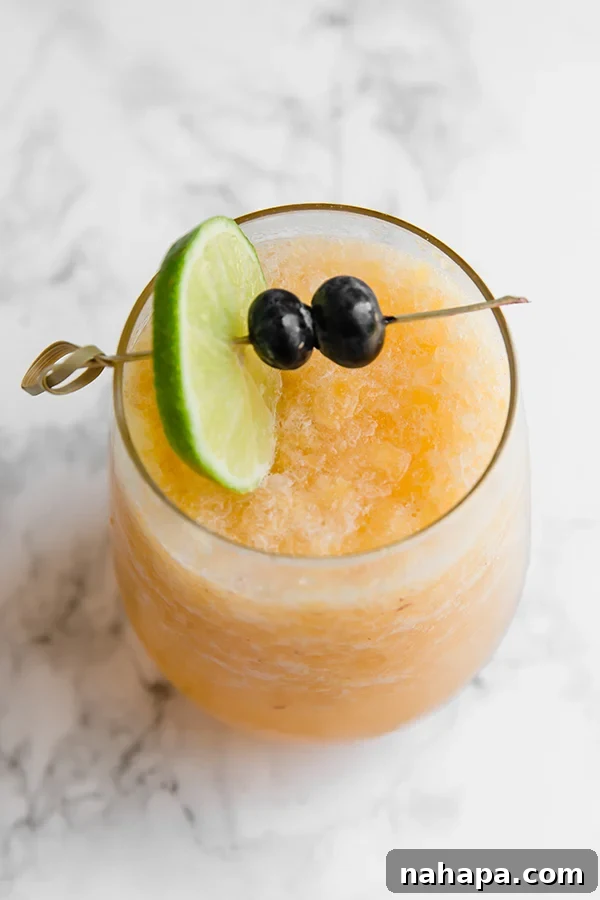 Frozen Peach Bellini Mocktail served in a tall glass with fresh peach slices