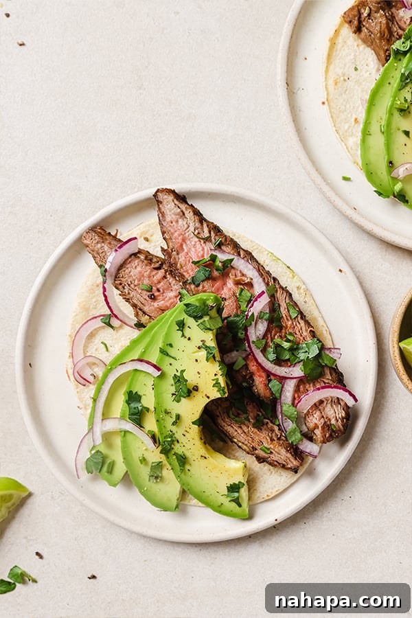 Sliced grilled flank steak with cilantro and lime wedges