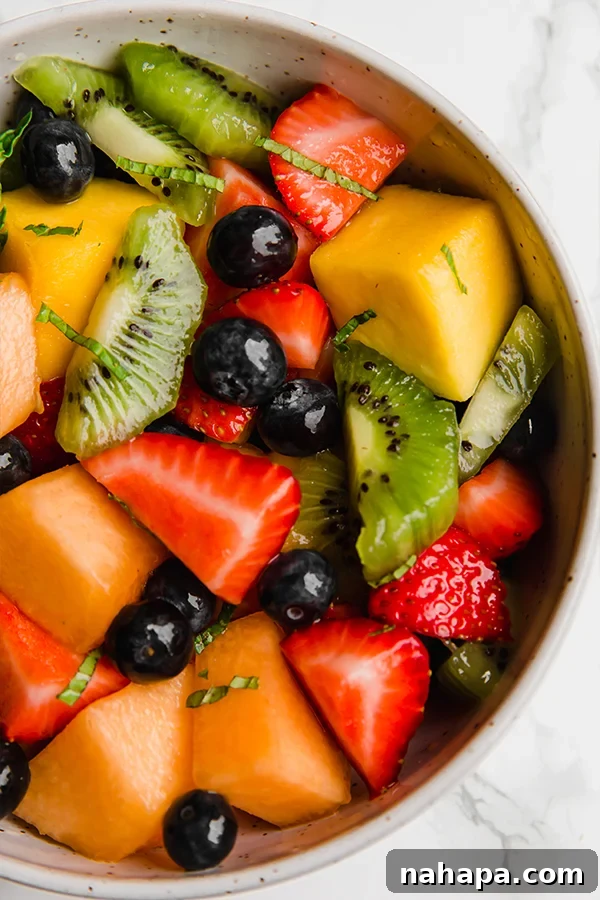 colorful fruit salad with mint leaves and lime wedges