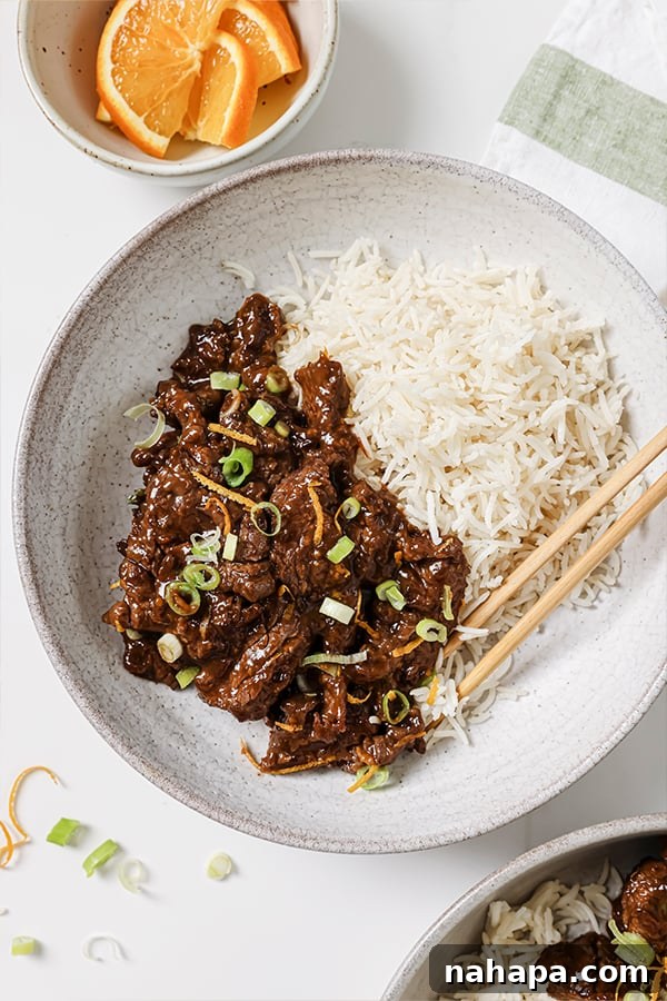 Zesty Orange Beef: A Gluten and Soy Free Treat 5 A bowl of healthy Paleo Orange Beef served with green onions and a side of cauliflower rice.