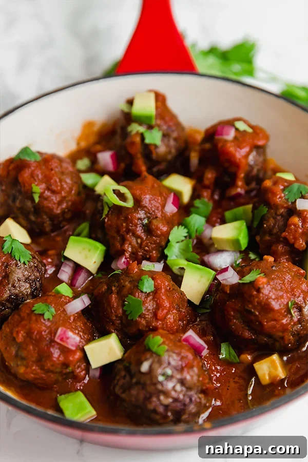 A vibrant close-up of fresh ingredients: red onion, avocado, and cilantro, highlighting the essential toppings for the enchilada meatball skillet.