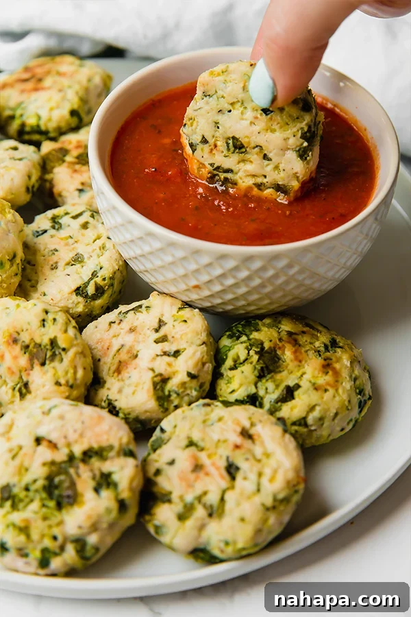 Close-up of baked Italian Chicken Poppers on a baking sheet, showcasing their golden-brown exterior and fresh herb flecks.