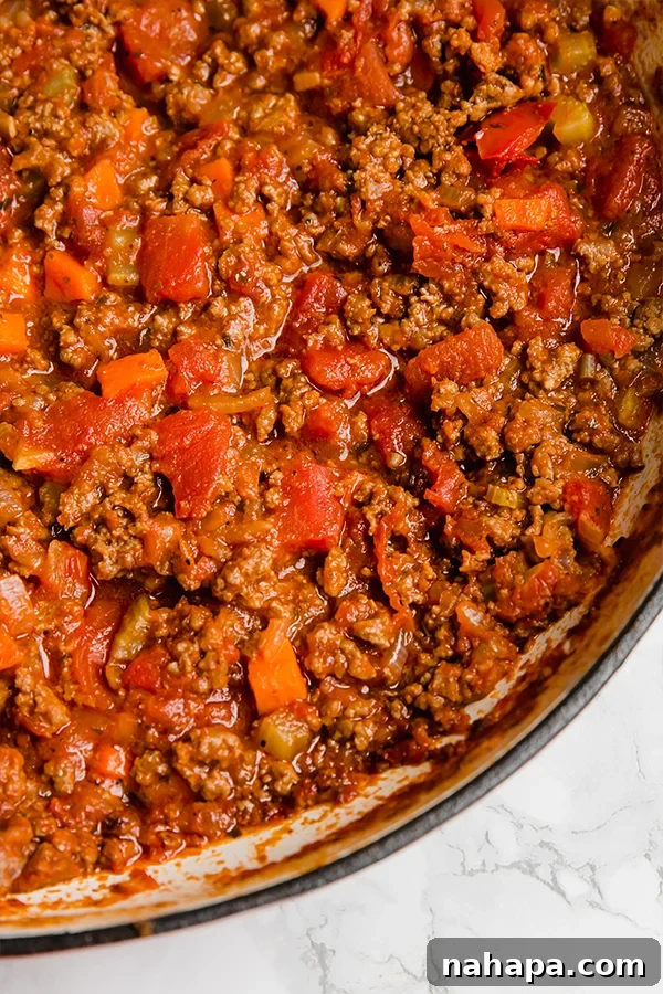 Cauliflower gnocchi being tossed with rich bolognese sauce in a pan.