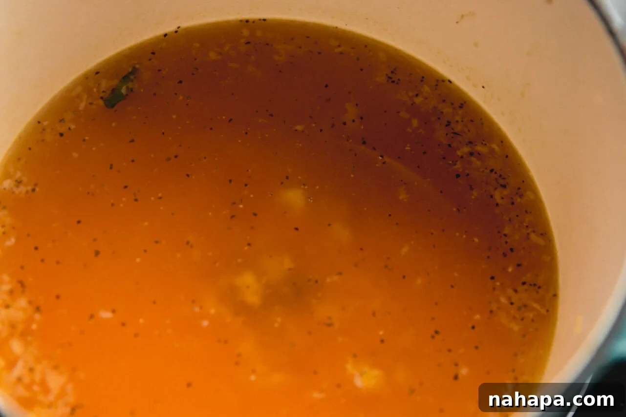 A Dutch oven gently simmering a rich, amber-colored broth on a stovetop, with steam visibly rising, indicating a warm and flavorful preparation.