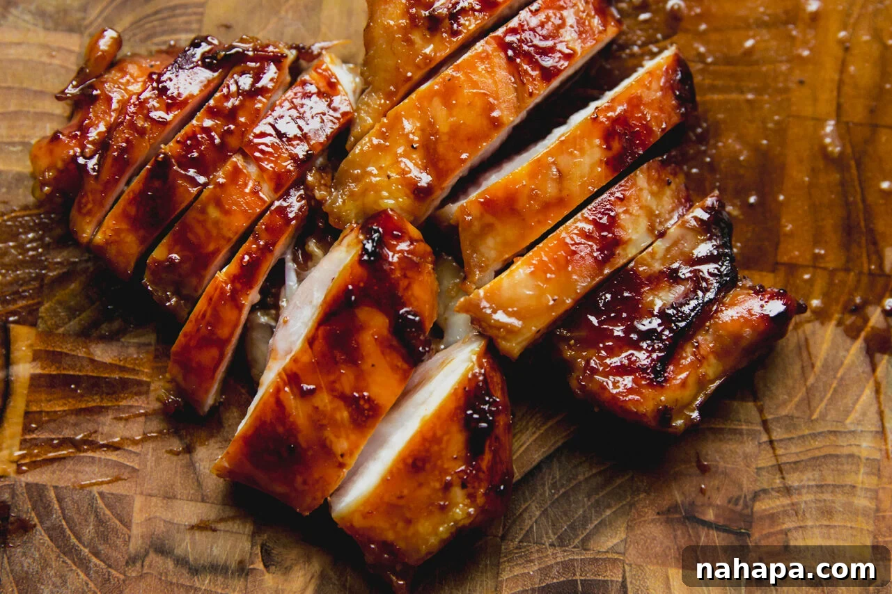 Two perfectly cooked and thinly sliced chicken thighs resting on a wooden cutting board, showcasing their juicy interior and golden-brown exterior.