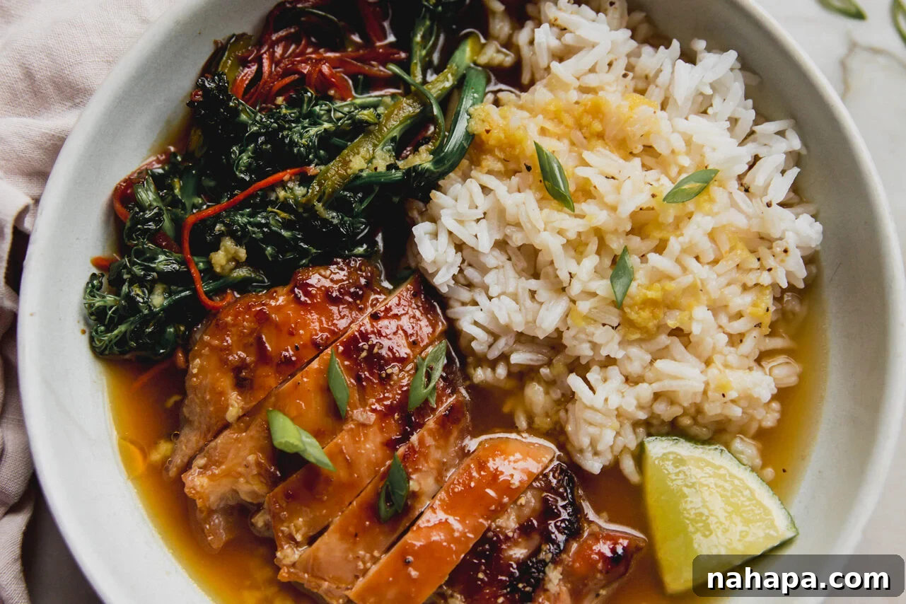 The final assembled bowl of brothy ginger chicken and rice, garnished with fresh green onions and a slice of lime, showcasing its inviting presentation.
