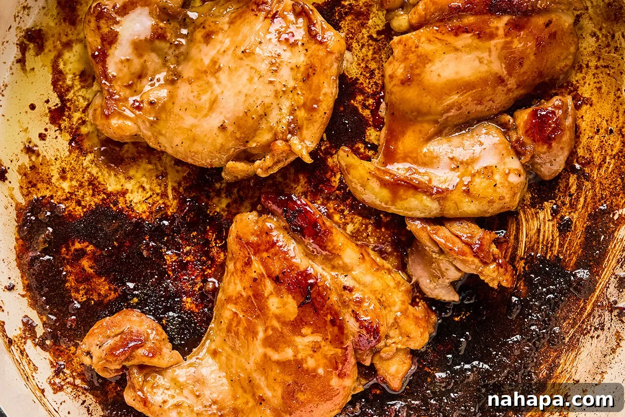 Sliced chicken pieces cooking to a golden brown in a hot pan on the stovetop, releasing a fragrant aroma.