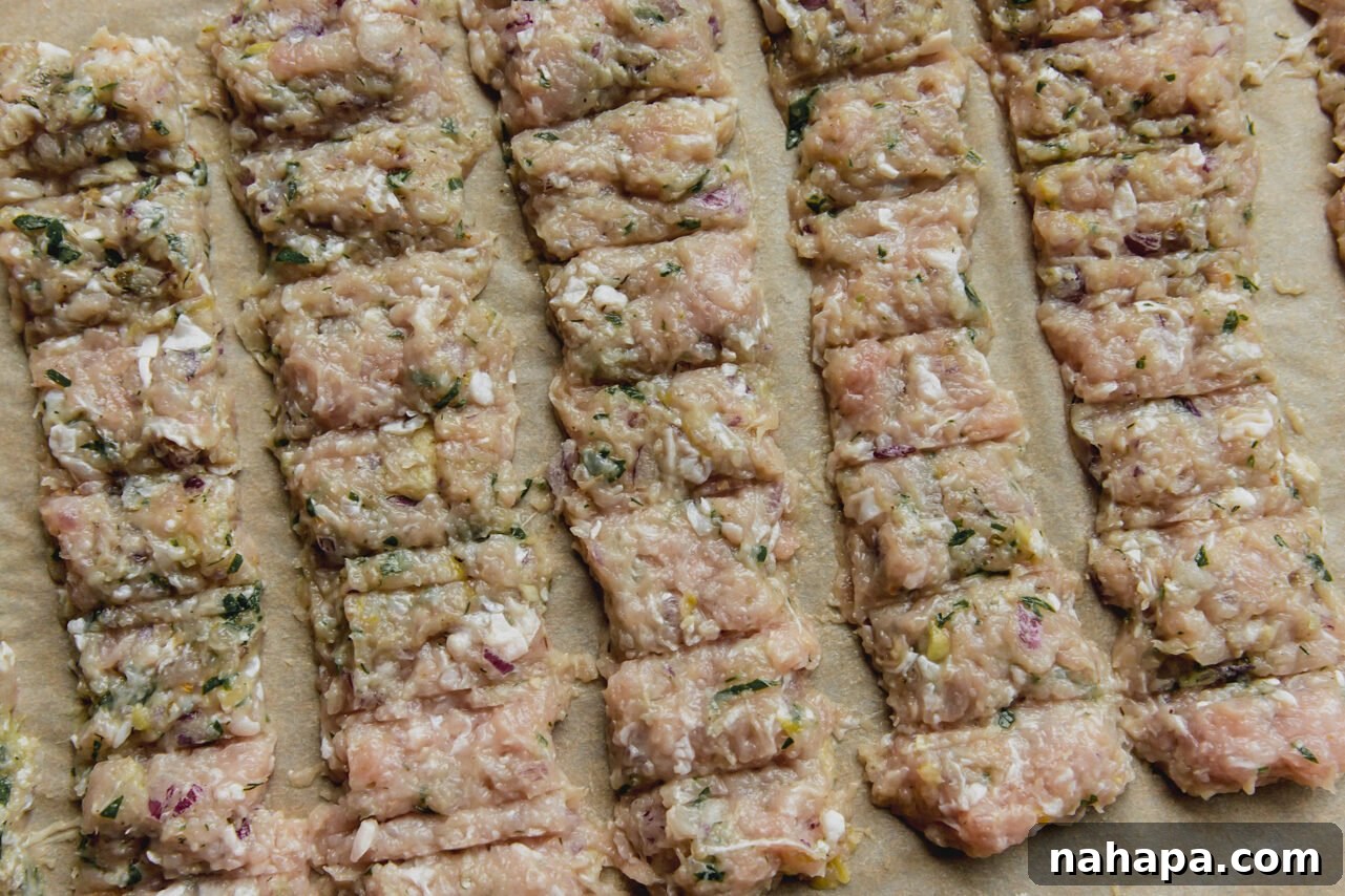 The chicken mixture pressed into an even layer on a baking sheet with scoring to mimic a kebab, ready for baking.