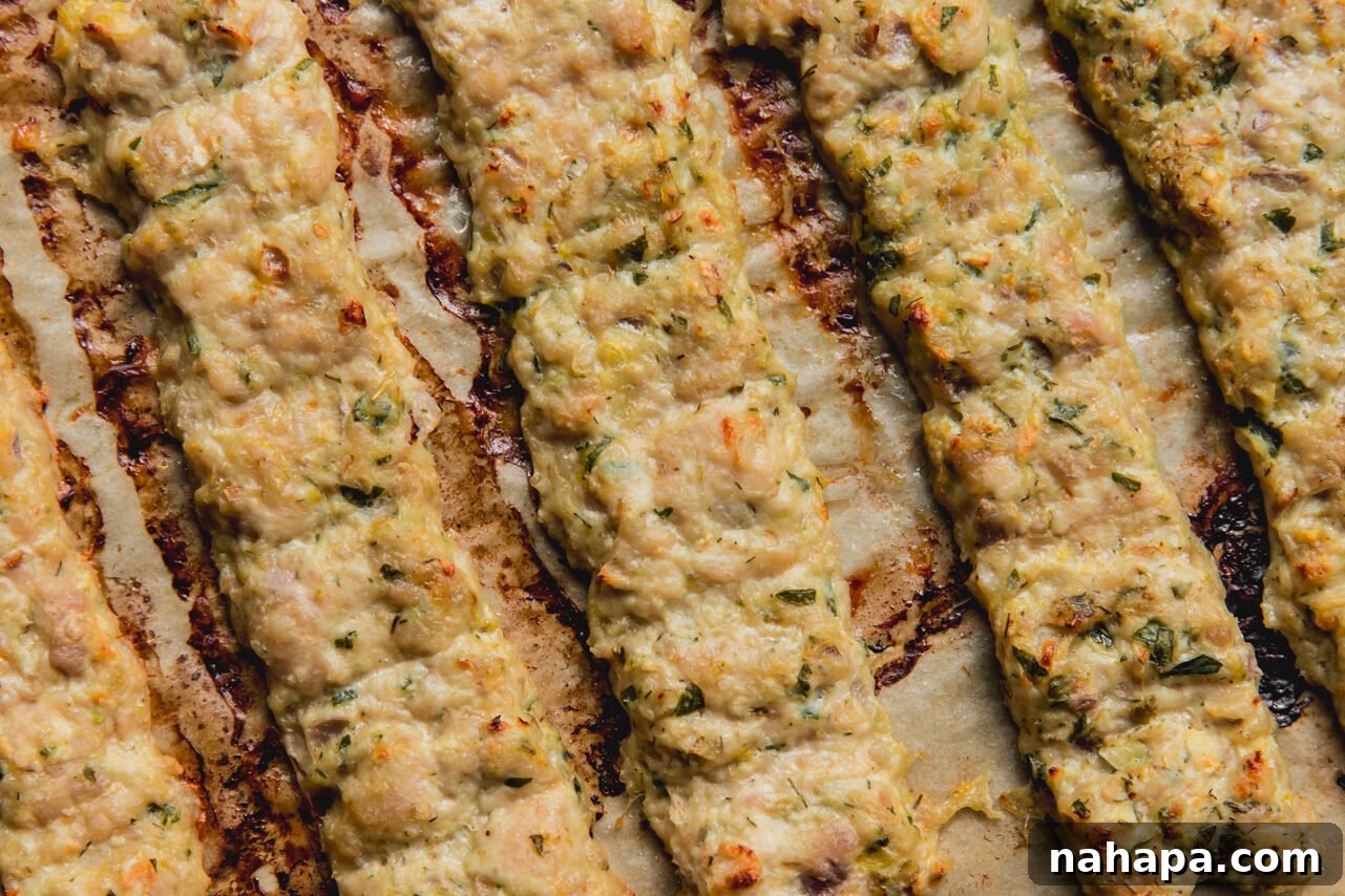 The ground chicken kebabs on a baking sheet after baking, golden brown and cooked through.