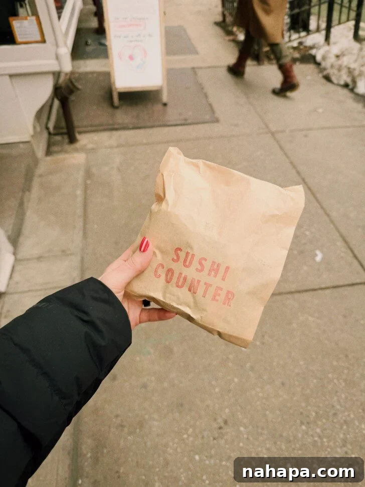 My Gluten-Free and Nightshade-Free NYC Food Guide 5 A hand holding a branded "Sushi Counter" paper bag against a blurred city sidewalk background, suggesting a convenient takeaway meal.