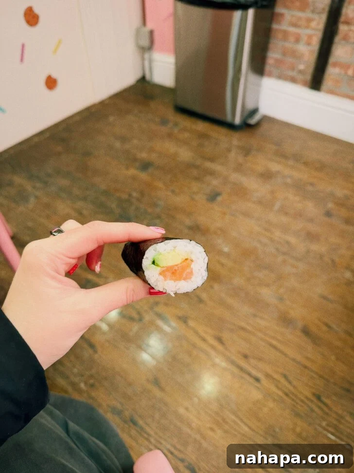My Gluten-Free and Nightshade-Free NYC Food Guide 6 A hand presenting a perfectly crafted salmon and avocado hand roll, highlighting the fresh ingredients and careful preparation.