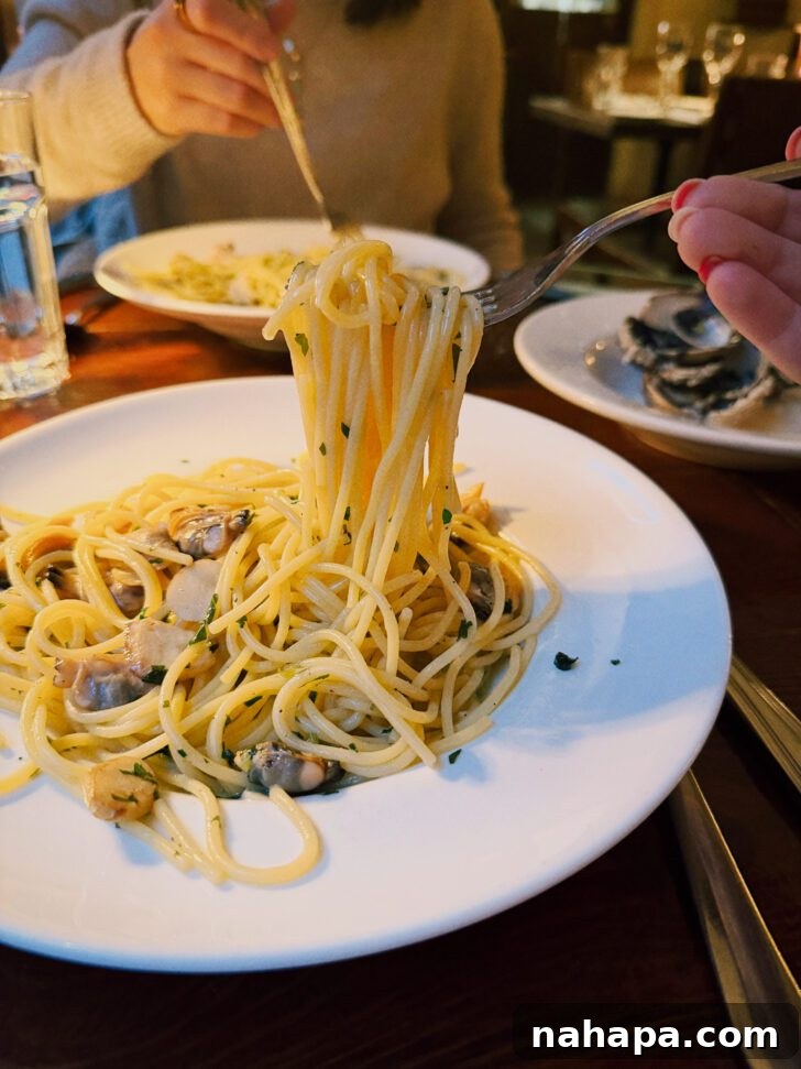 My Gluten-Free and Nightshade-Free NYC Food Guide 7 A generous bowl of linguine and clams, perfectly cooked, with a fork ready to twirl the pasta, highlighting the inviting texture and savory sauce.