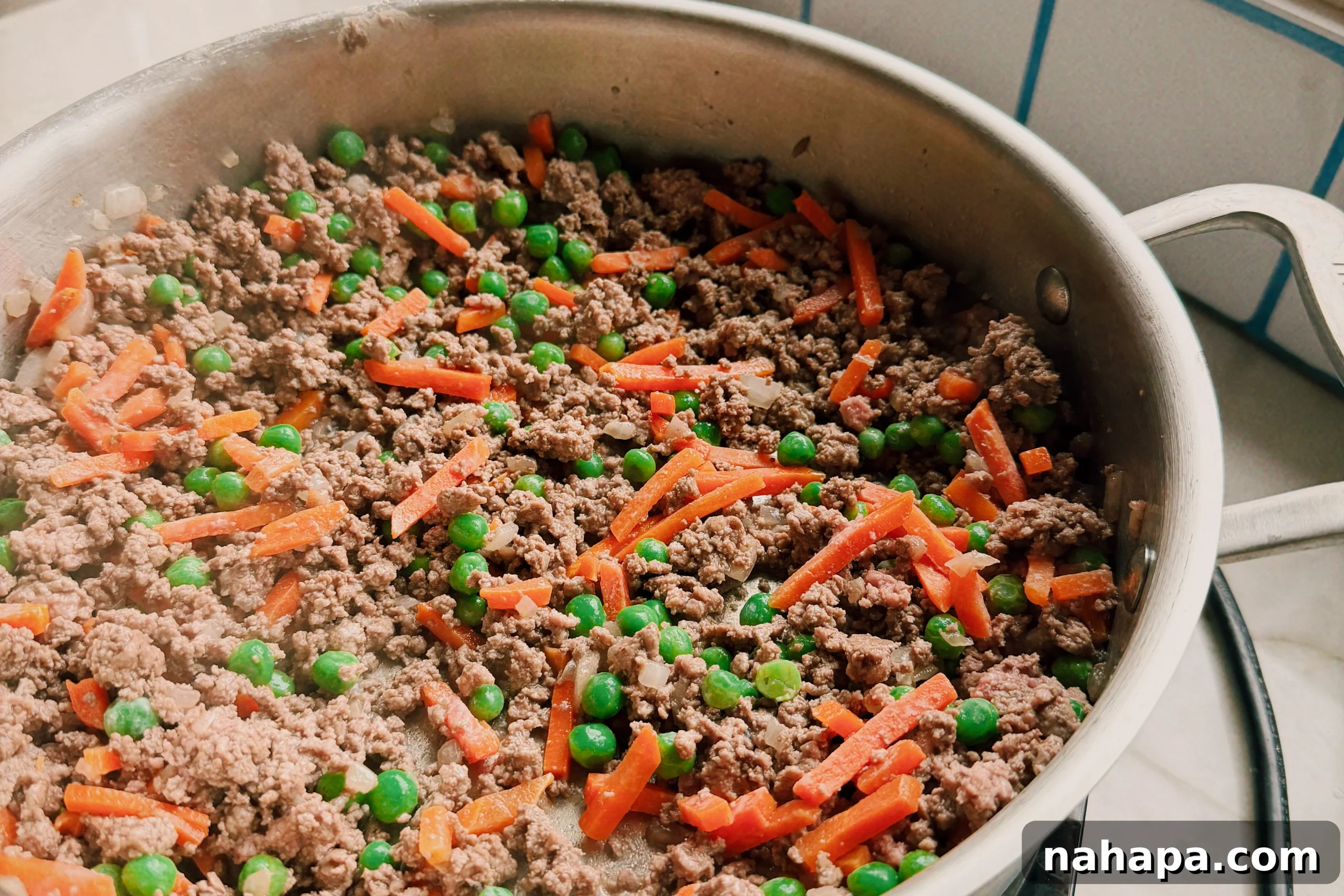 A saute pan with ground beef and veggies in it.