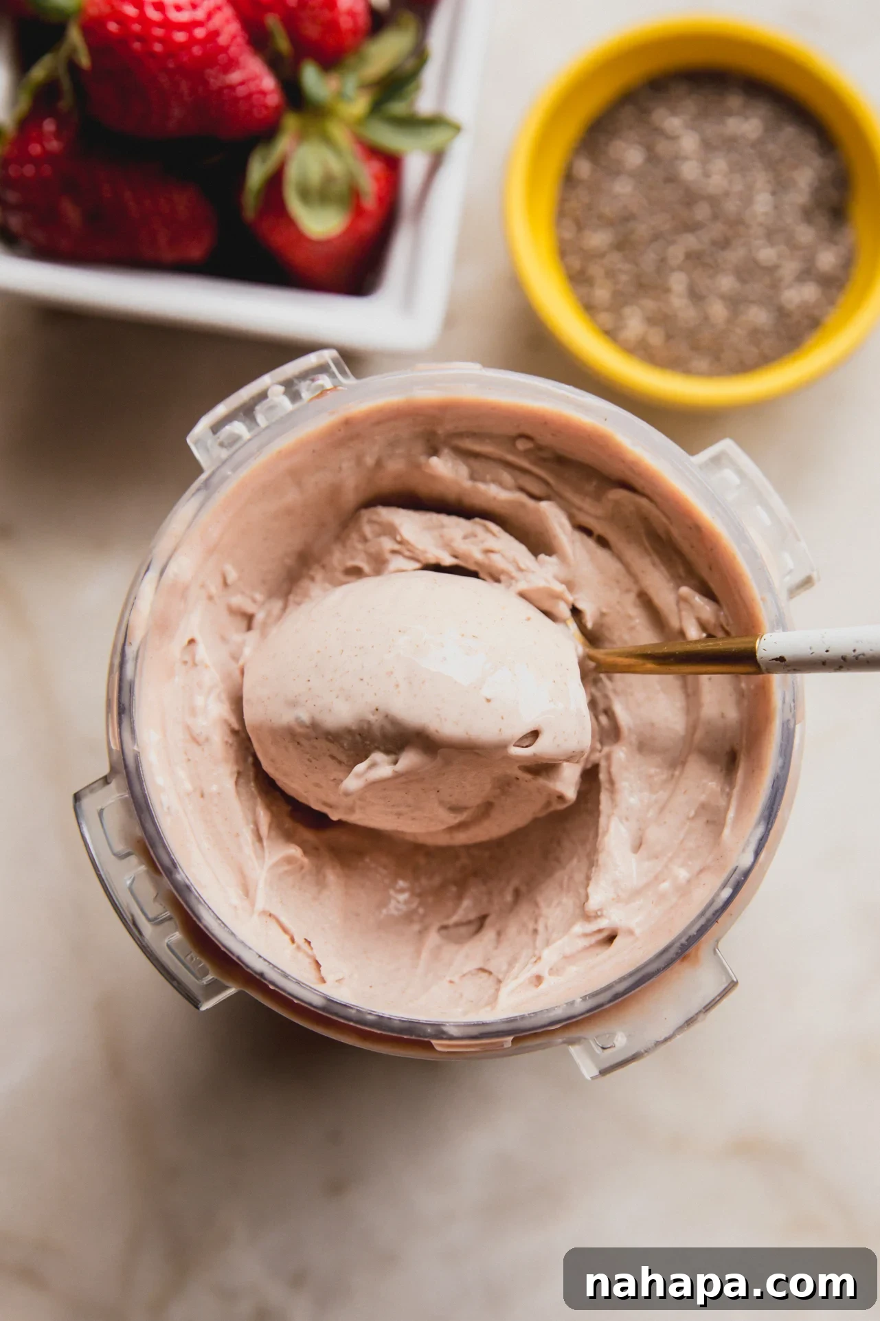 An inviting overhead shot of the Ninja Creami pint filled with creamy chia seed ice cream, a spoon resting in it after scooping, highlighting its smooth and rich texture.