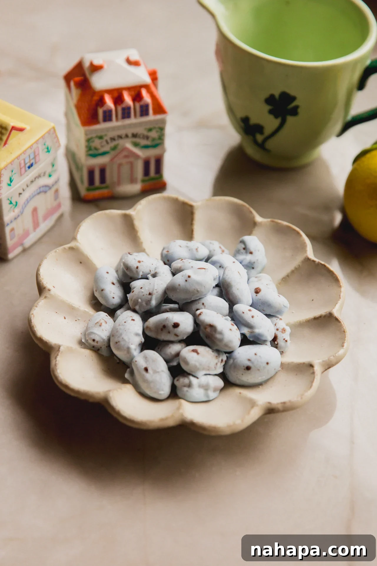 A bowl filled with beautifully blue chocolate-covered almonds, speckled with brown, resembling robin's eggs, surrounded by spring kitchen decor.