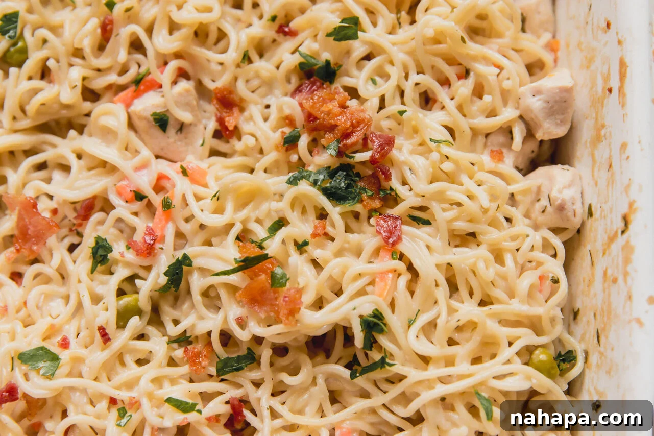 Bacon ranch ramen bake topped with parsley and bacon in a large casserole dish.