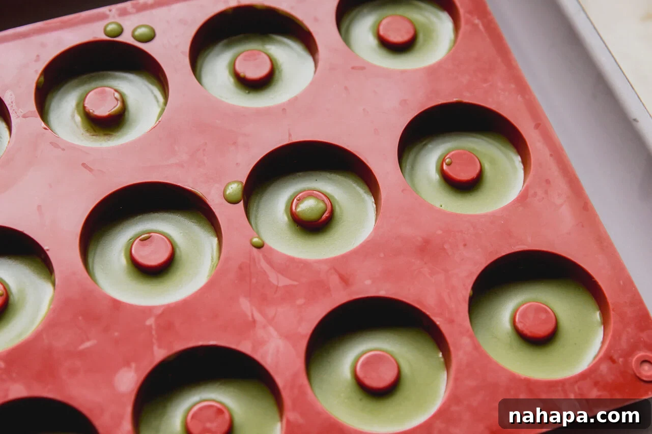 A mold filled with the matcha layer on top of the orange mango layer.