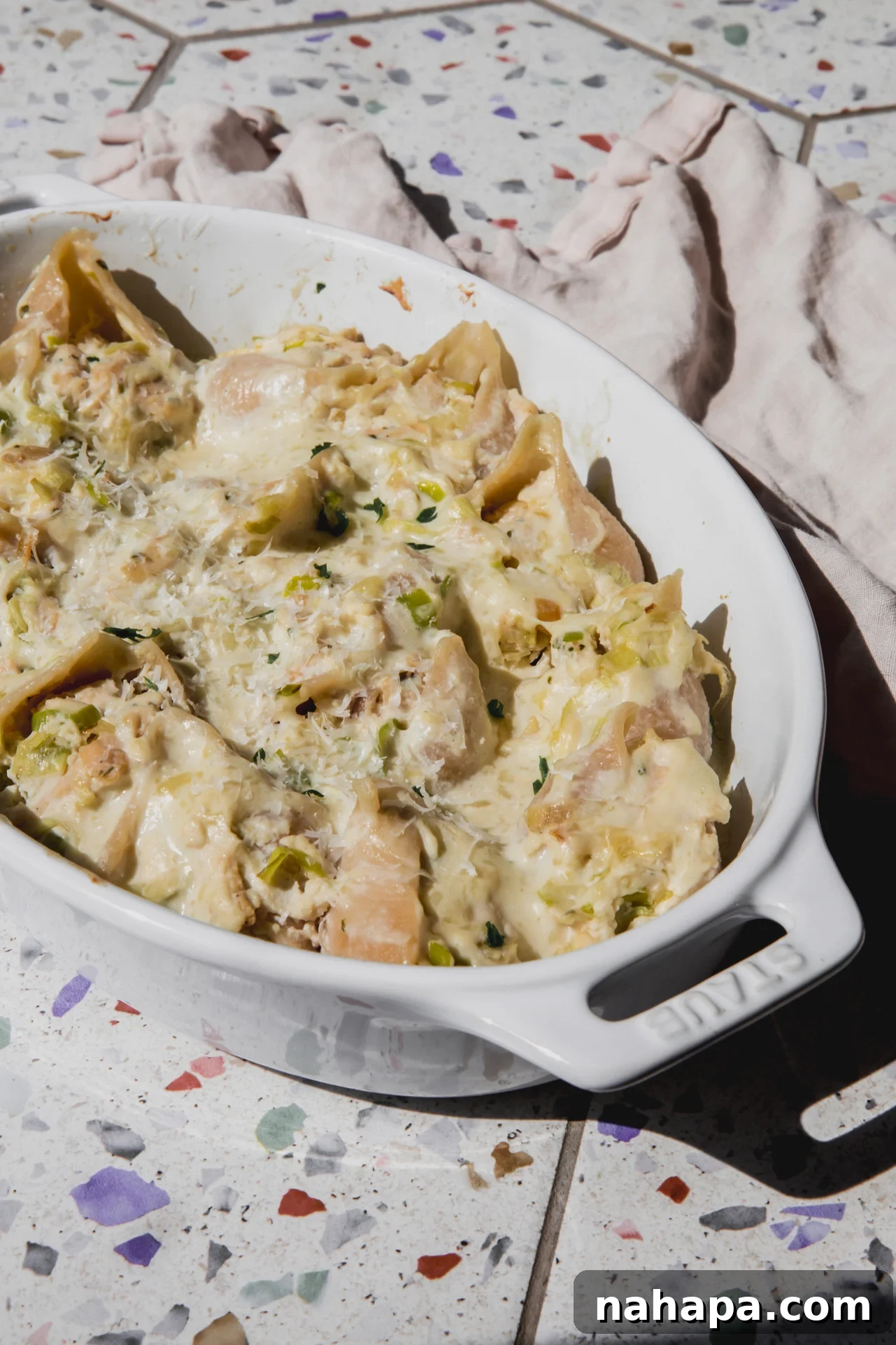 Creamy chicken stuffed shells topped with parsley with an oval baking dish.