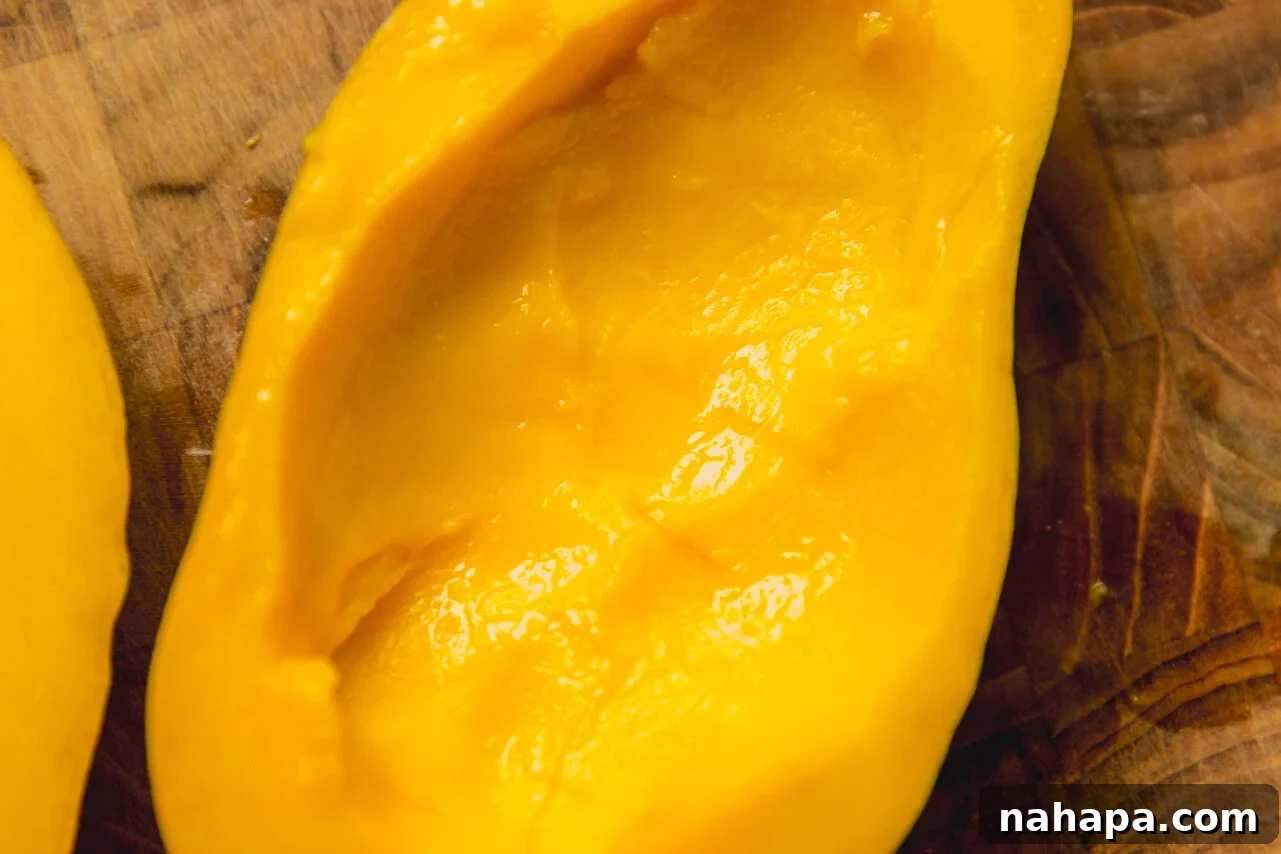 A hallowed out mango half sitting on a wooden cutting board.