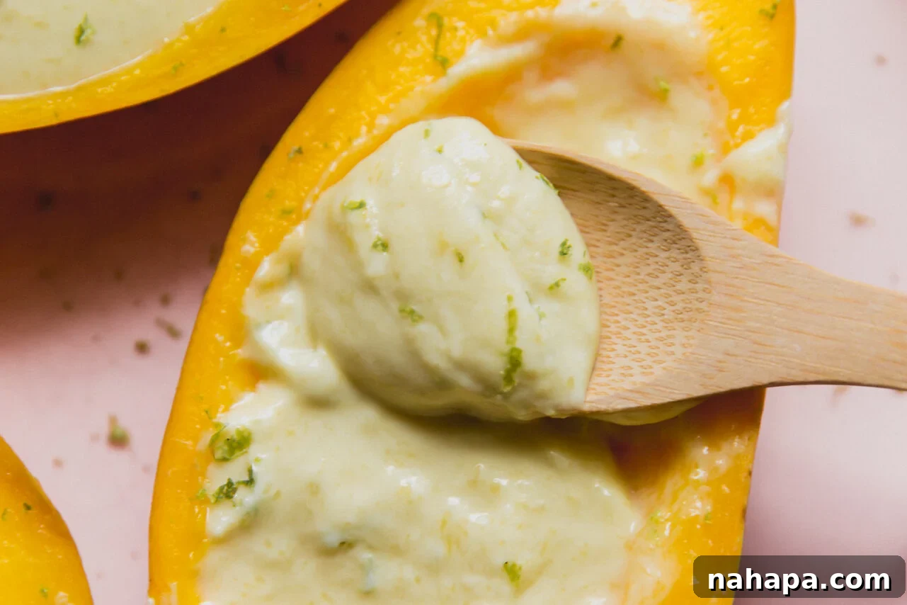 Mango posset topped with lime zest, and a wooden spoon dipping the creamy filling.