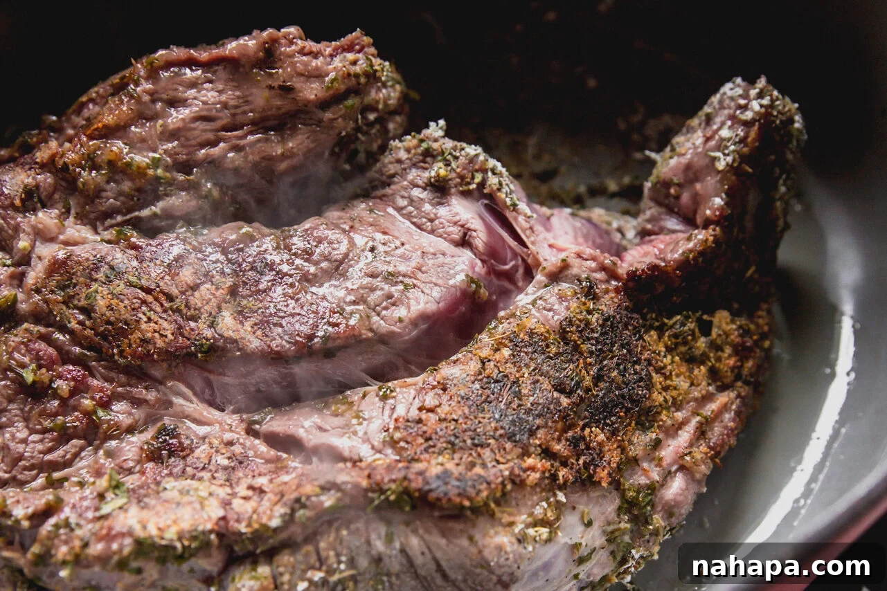 A Dutch oven with a chuck roast searing to a golden brown on all sides.