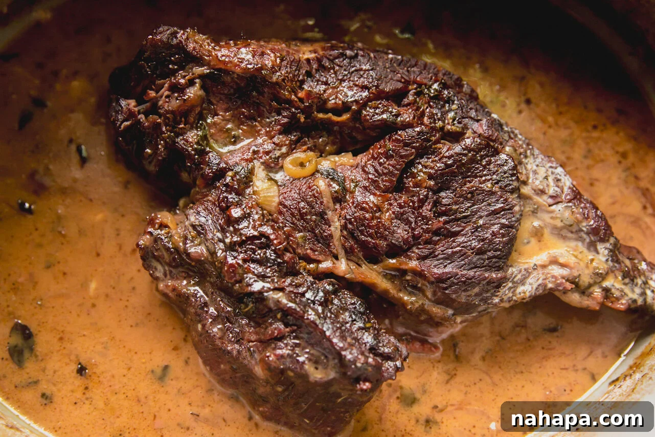 The Dutch oven filled with the seared chuck roast with red wine vinegar added in, deglazing the pan.