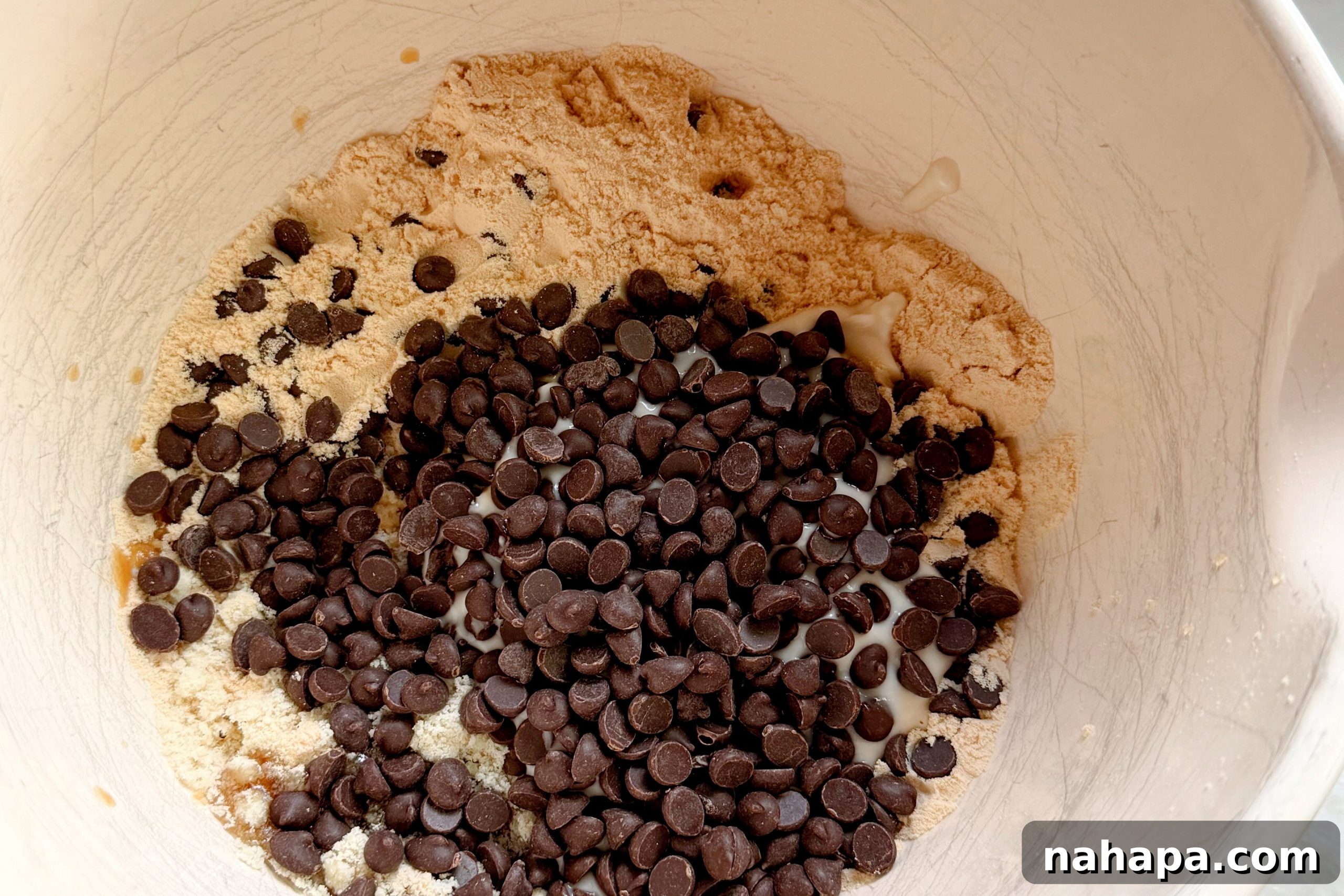 A white bowl filled with all the ingredients for protein cookie dough before mixing it together to form the dough.