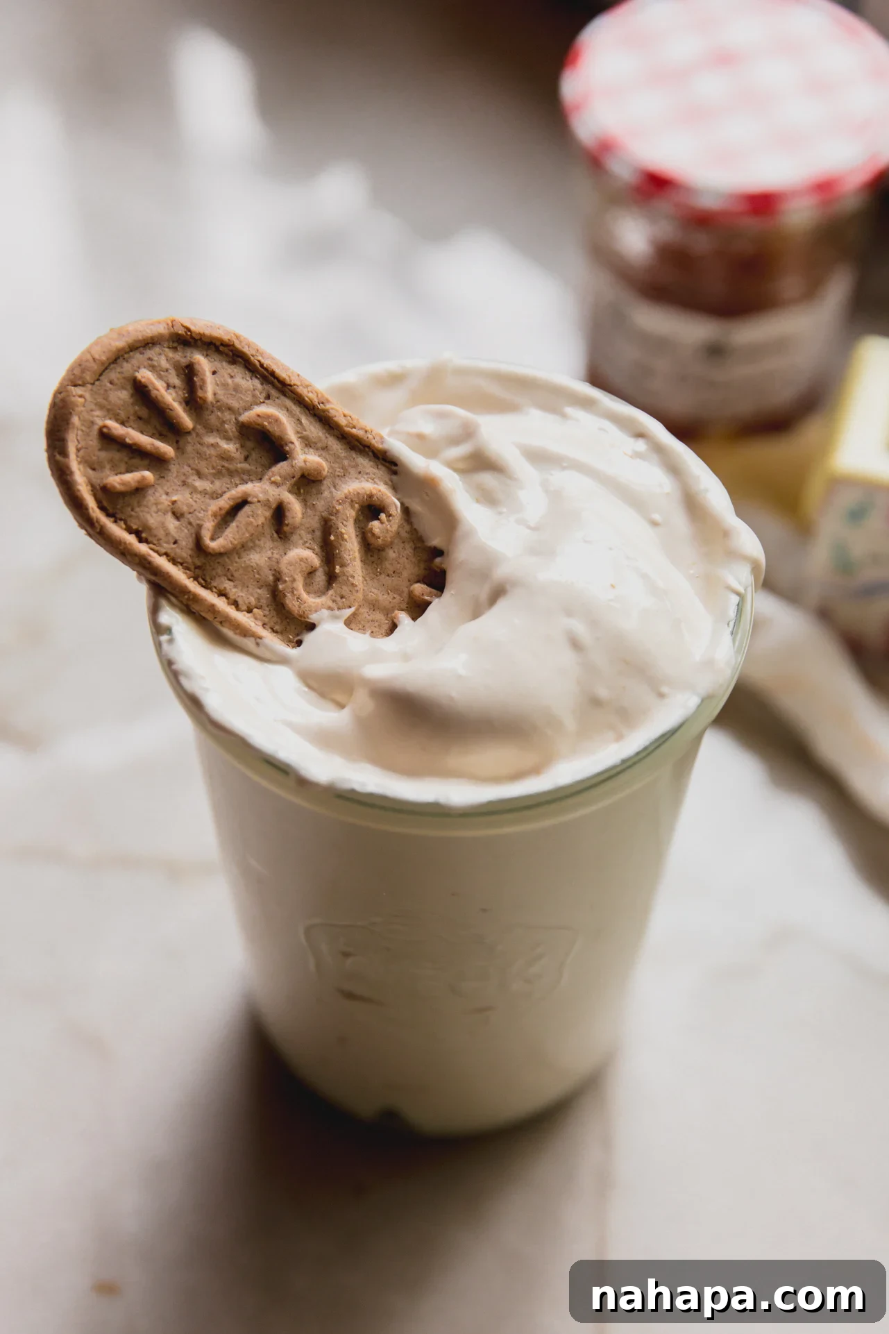 A glass cup filled with peach vanilla marshmallow fluff with a biscoff cookie on top.