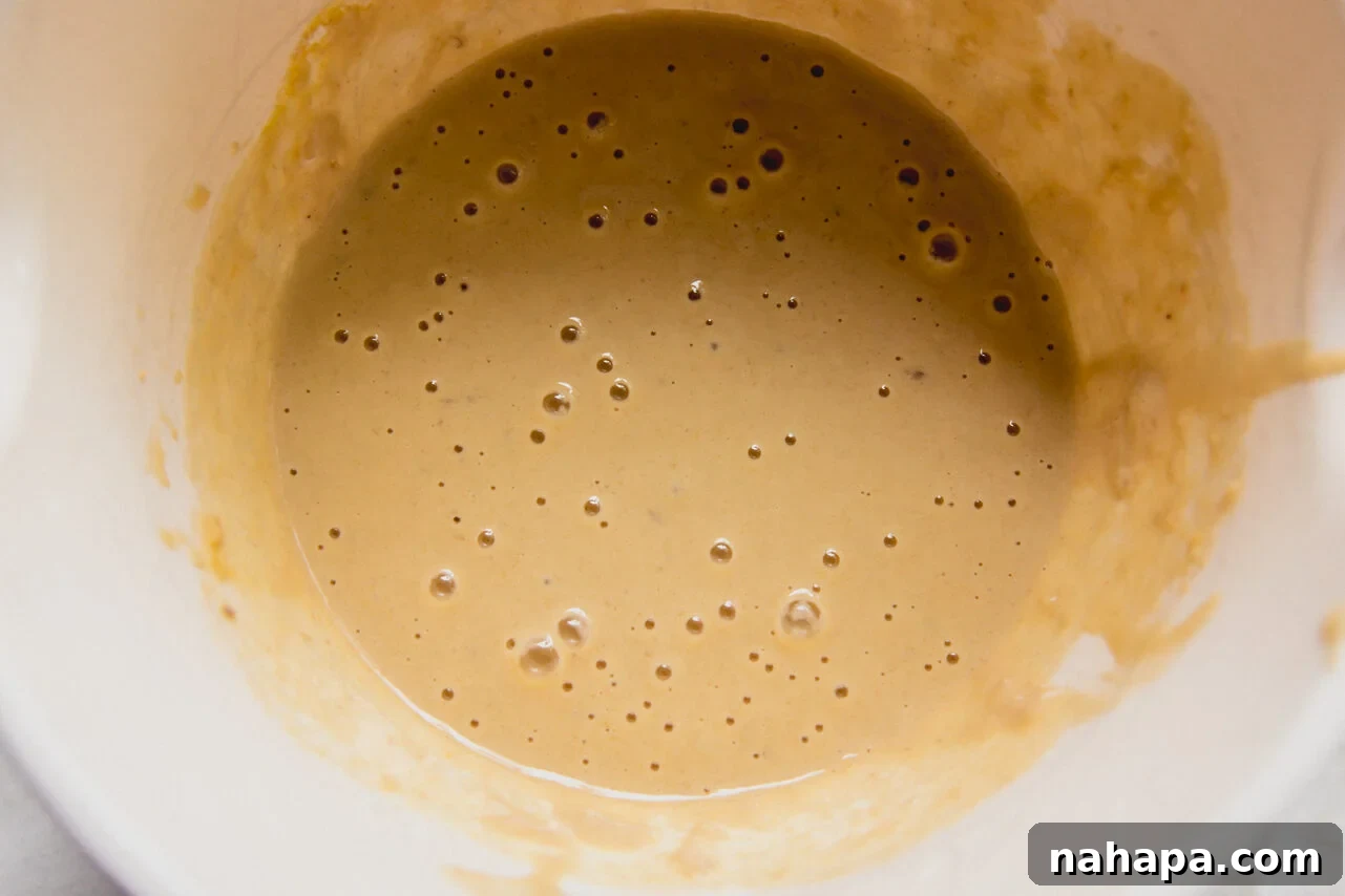 A white ceramic bowl with batter for berry protein breakfast cake in it.