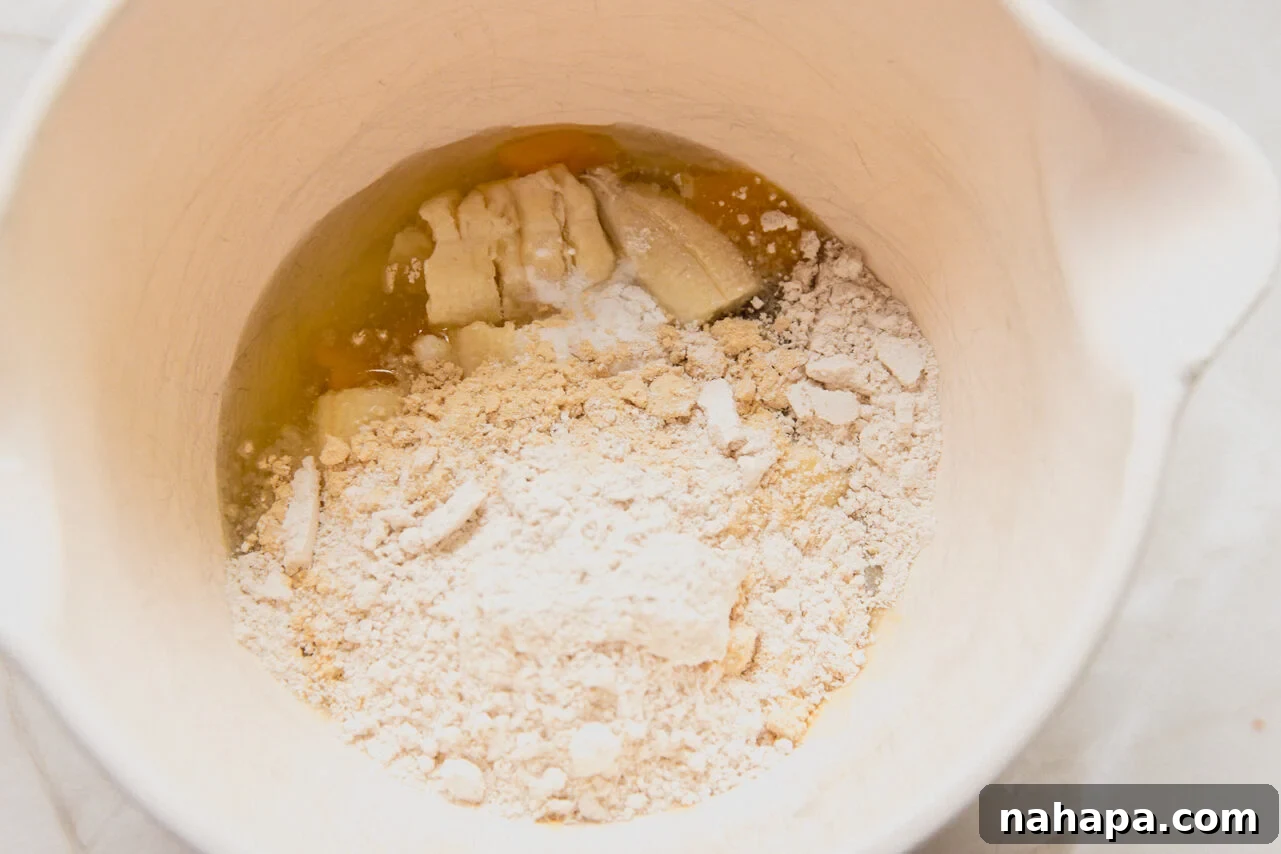 A white ceramic bowl with banana, flour, and protein powder added to the bowl before blending it.