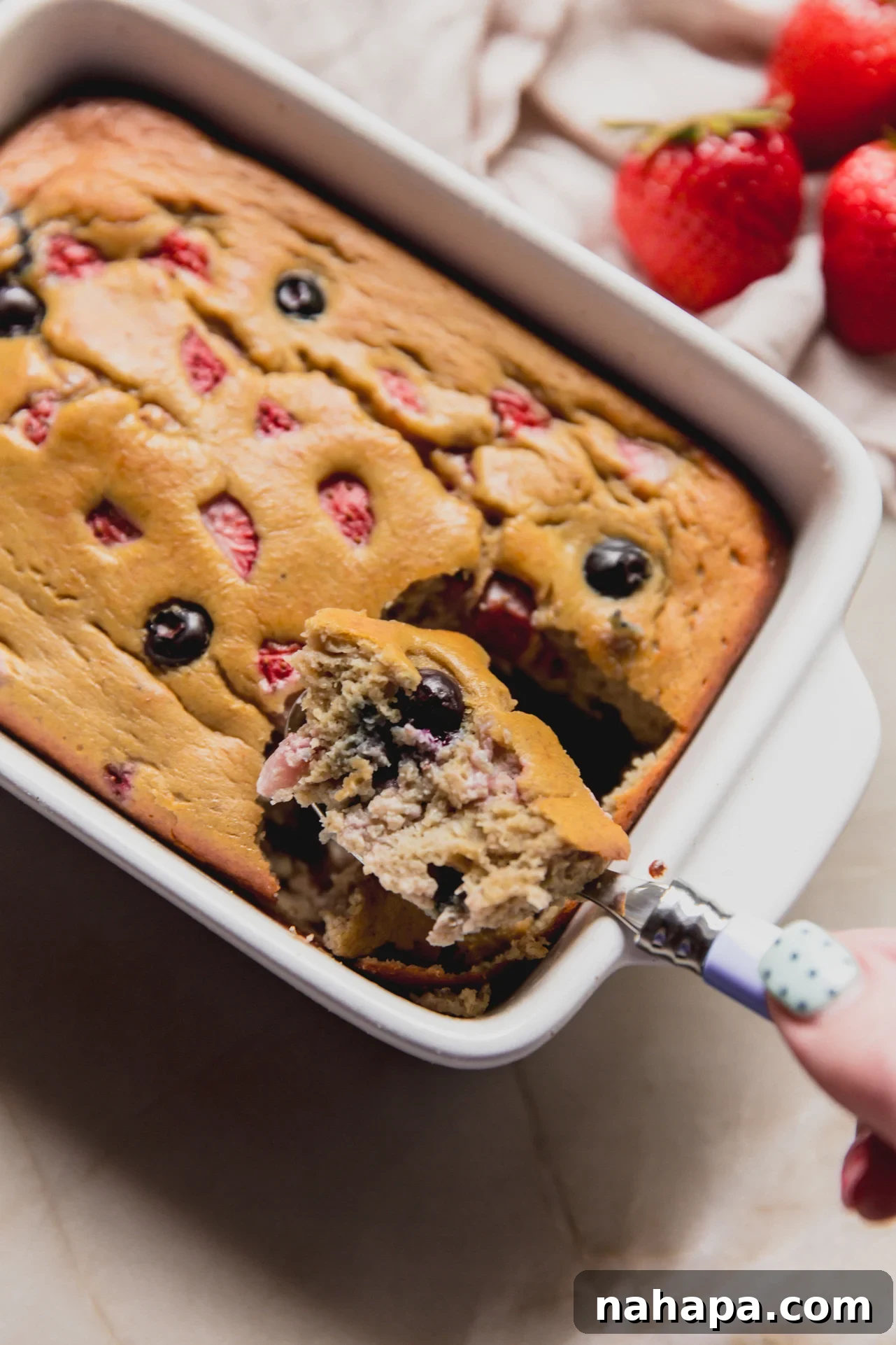 A spoon taking a scoop out of the berry protein breakfast cake.