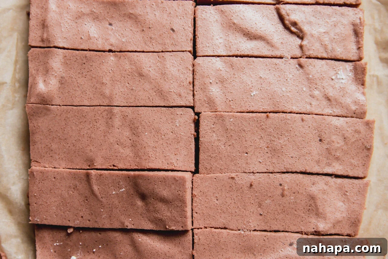 The marshmallows after setting in the fridge cut into 10 bars sitting on a piece of parchment paper.