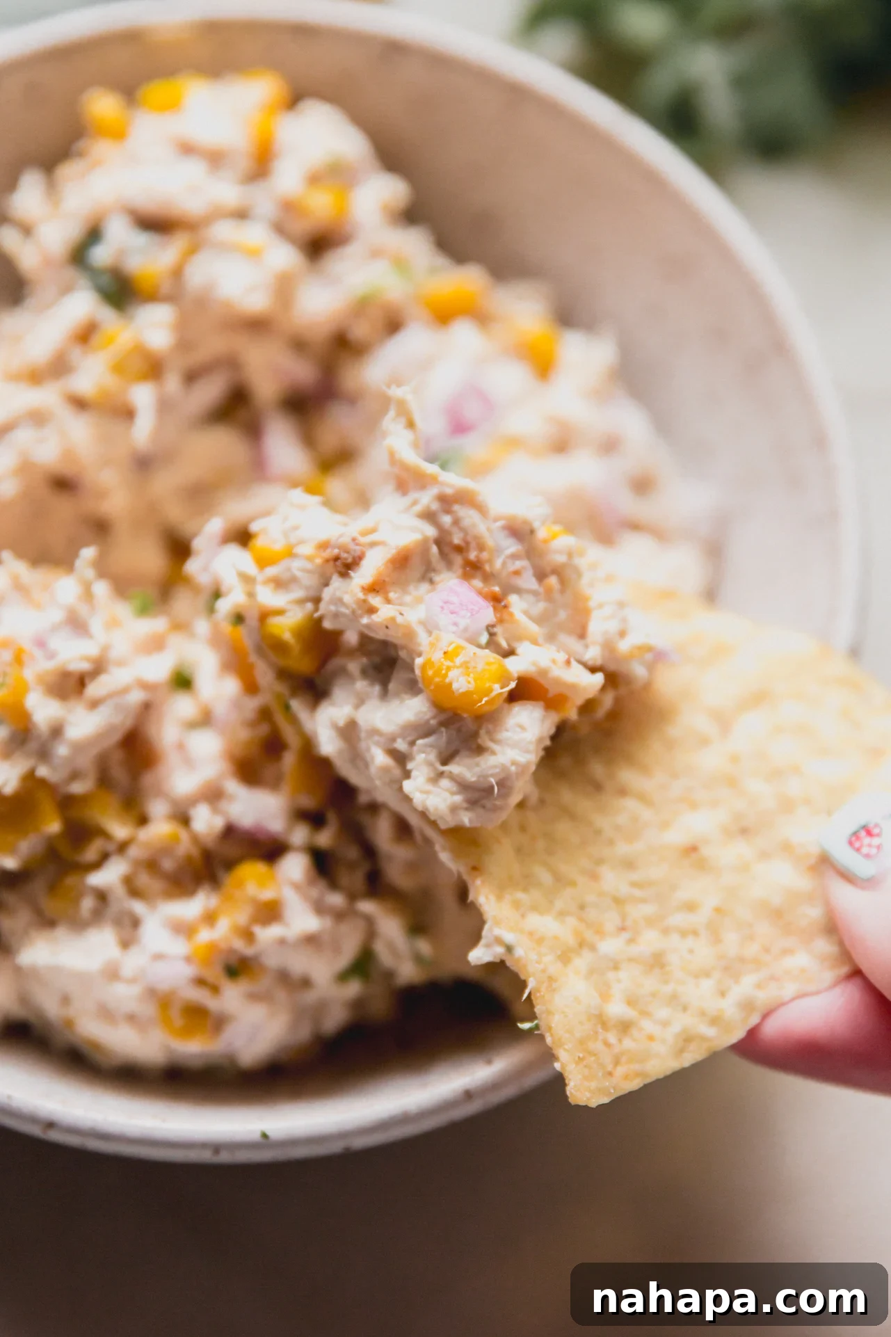 Mexican Street Corn Chicken Salad Recipe for Summer BBQs 9 A chip taking a chunk of street corn chicken salad from the bowl.