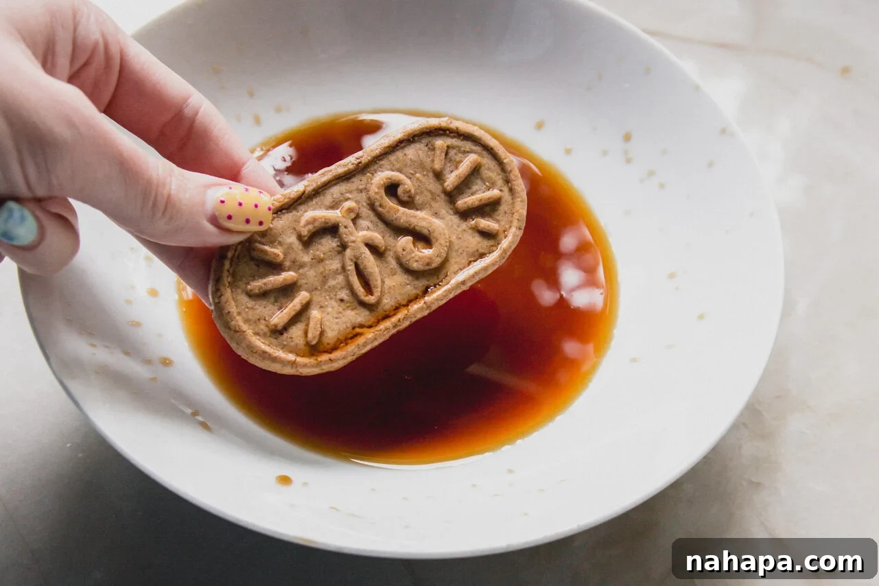 A breakfast biscuit being dipped into coffee in a white bowl by a hand.