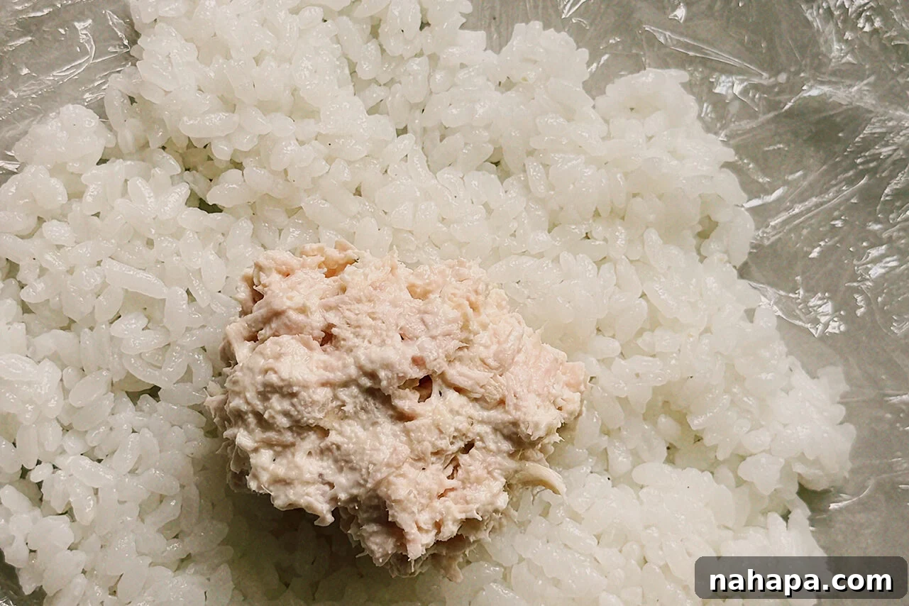 Tuna Onigiri Shaped Like Soccer Balls 6 Cling wrap filed with a layer of rice and a scoop of tuna salad in the middle.
