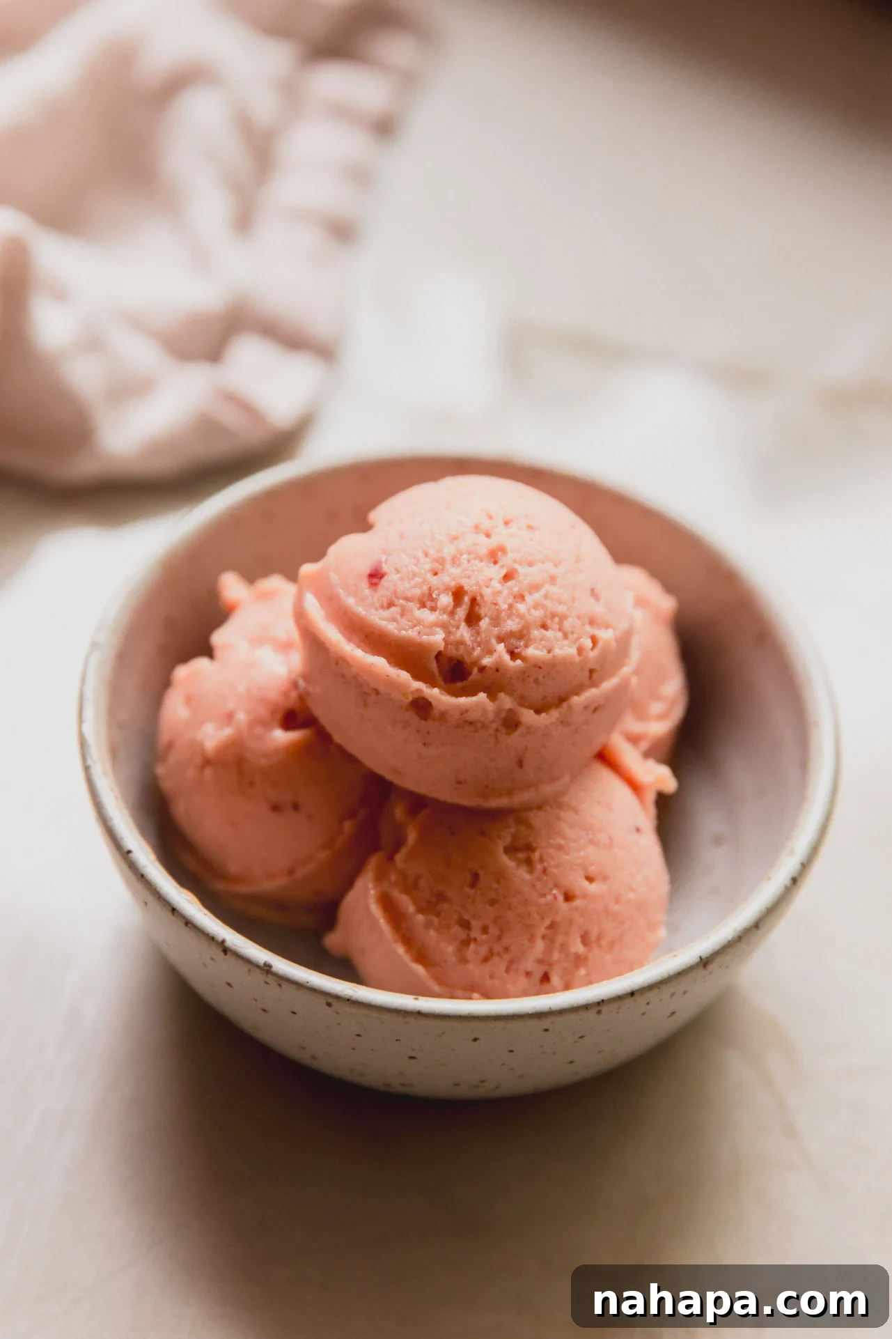 Three scoops of peach sorbet in a small bowl.