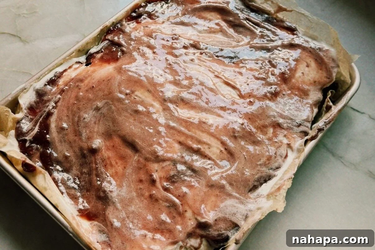 Rectangular cake pan topped with ice cream and jam.
