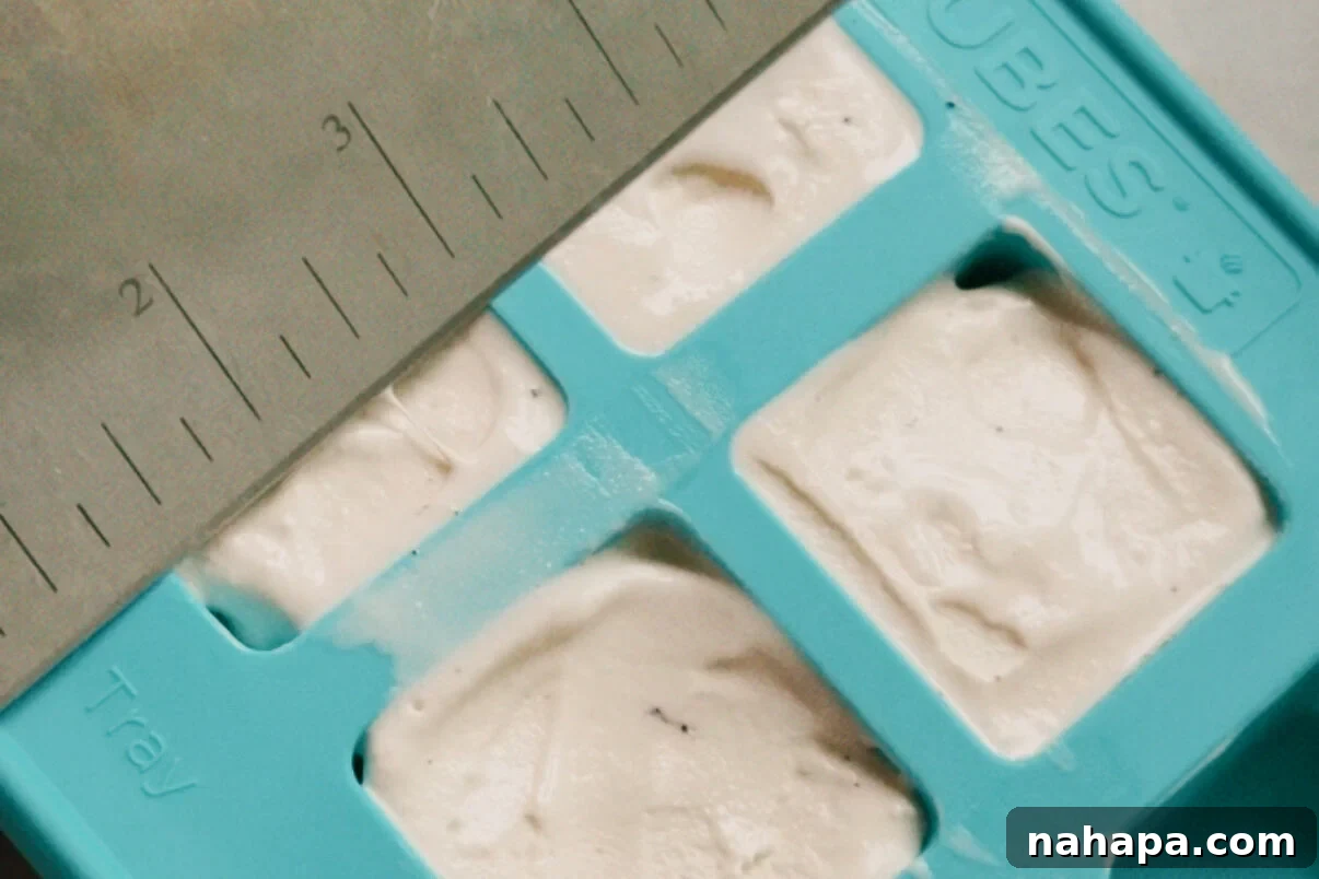 The silicone molds filled with ice cream being leveled off.