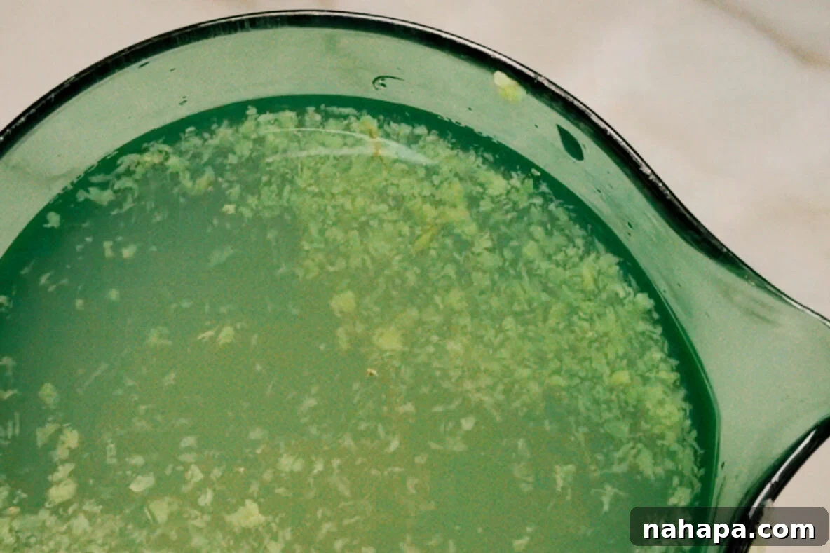 A glass measuring cup of the water, lemonade, and grated ginger mixture.