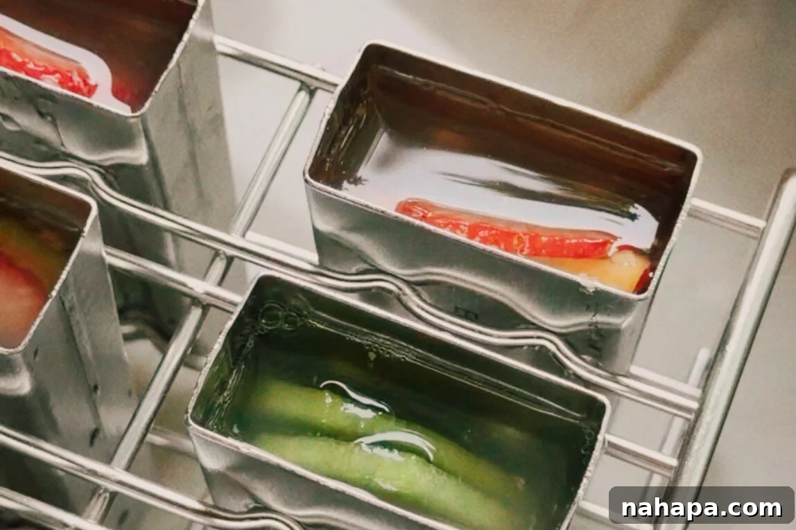 The popsicle molds with fruit and liquid in them before freezing.