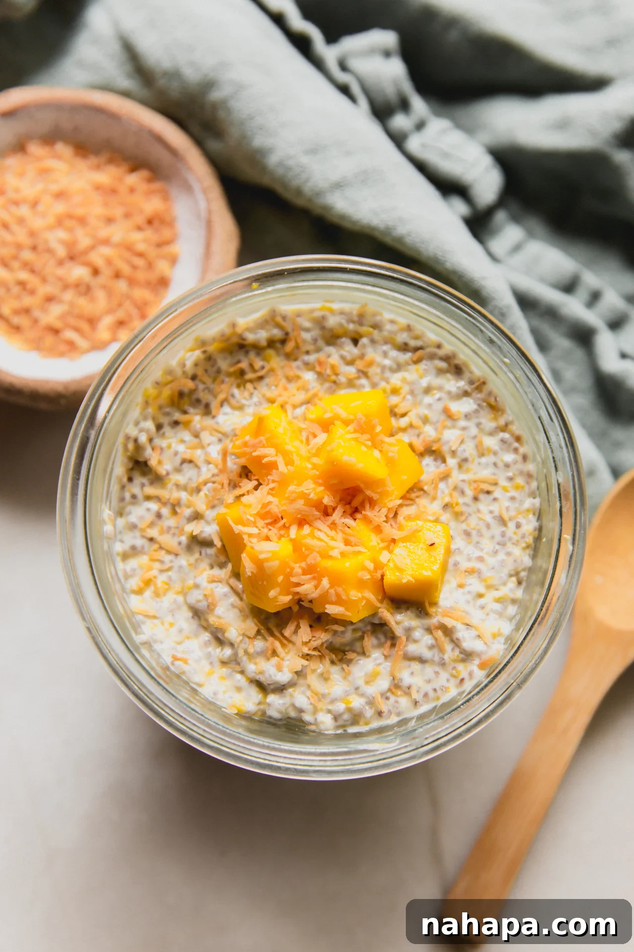 Mango chia pudding in a cup topped with diced mango and toasted coconut