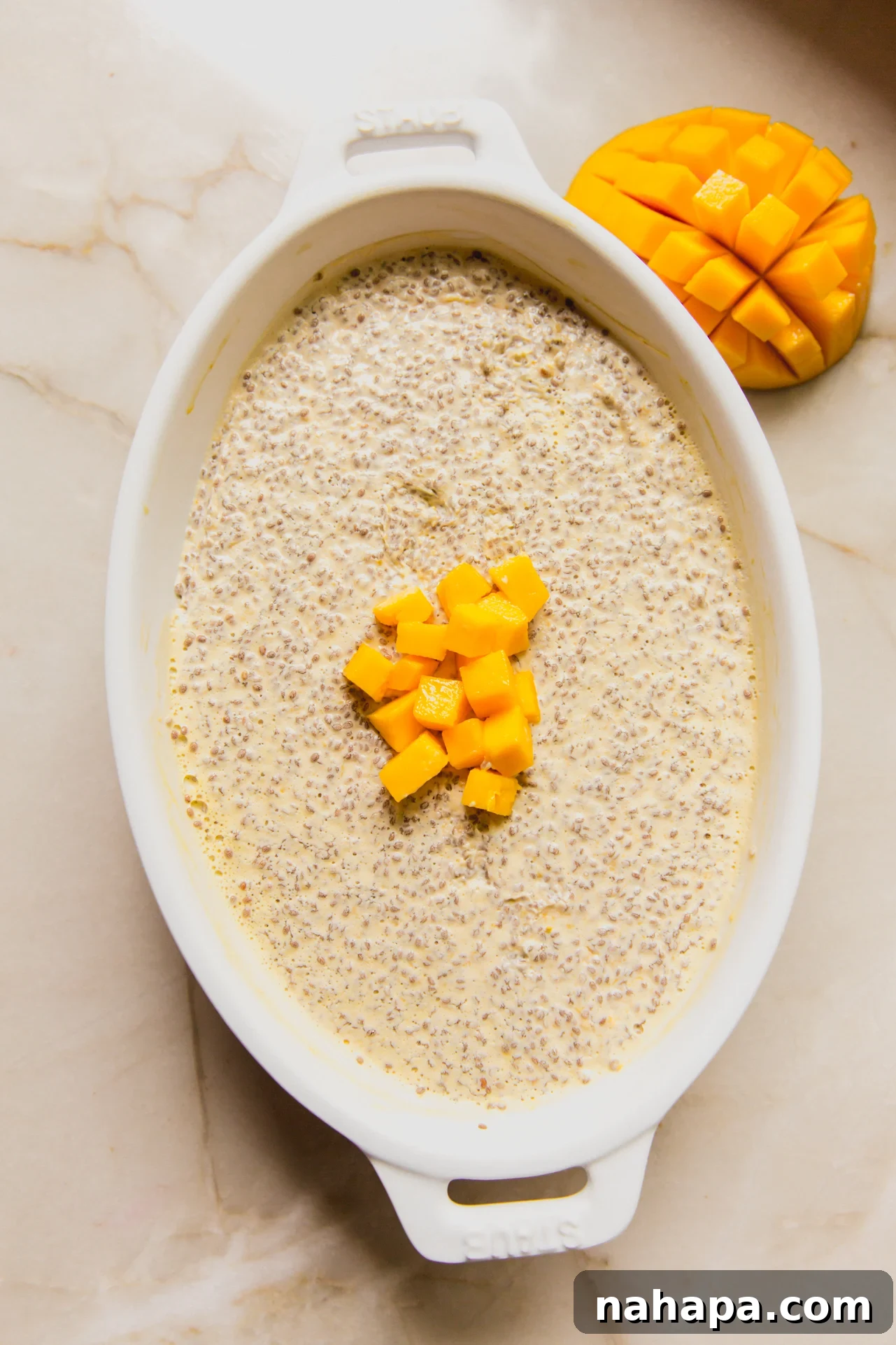 Mango chia pudding in a large white baking dish topped with extra diced mango