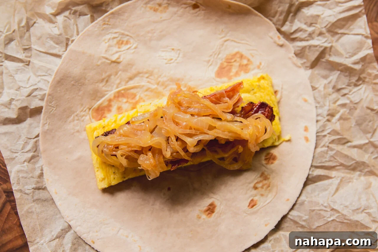 Caramelized Onion Breakfast Burritos with Eggs and Cheese 6 A caramelized onion breakfast burrito after being assembled with eggs, bacon, and onions before being rolled.